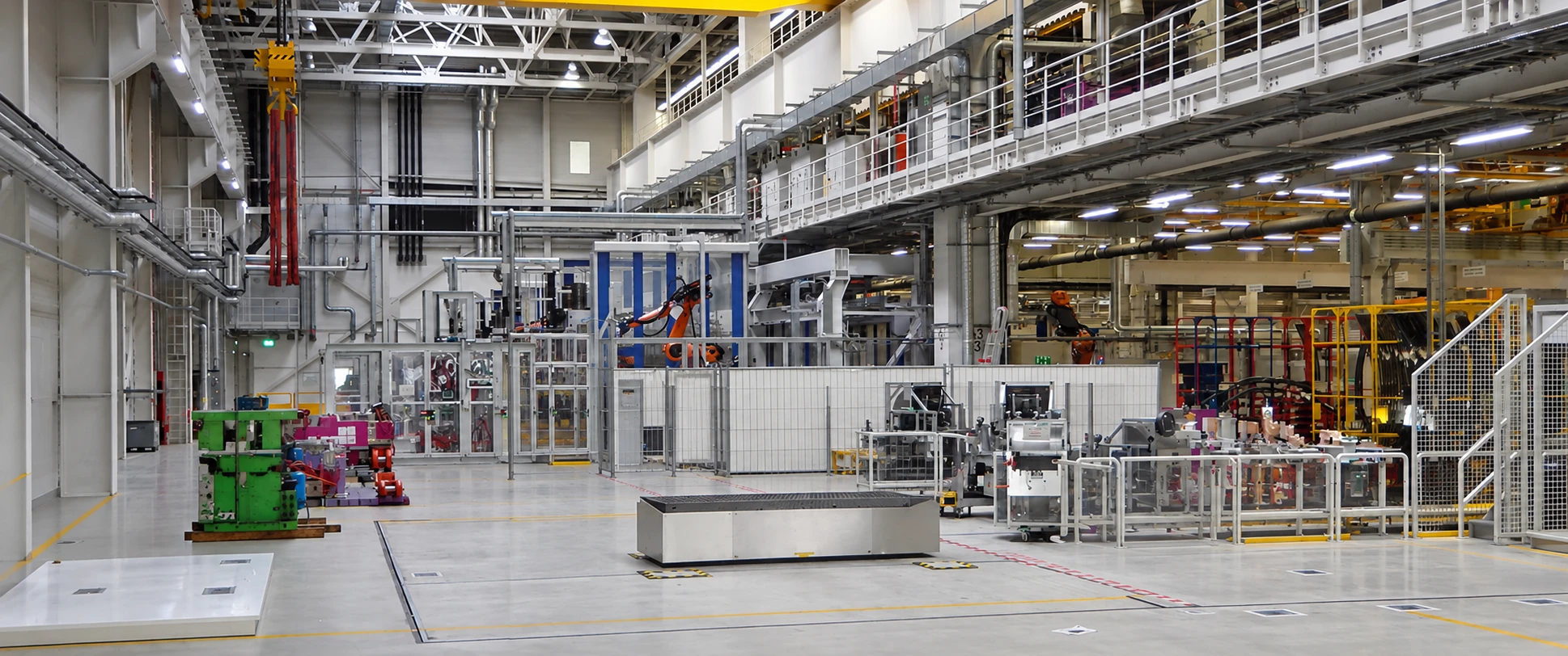 Retuschierte Innenaufnahme einer Produktionshalle des BMW-LaKa-Projekts in Leipzig, ohne die Karosserien und mobilen Behälter im Vordergrund.